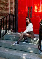 girl sitting in front of a red door