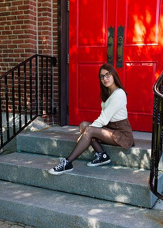 girl sitting in front of a red door
