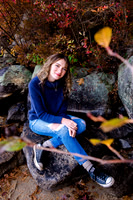 Girl sitting on a rock in fall background
