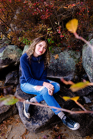 Girl sitting on a rock in fall background